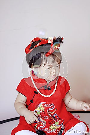 Cute Chinese little baby in red cheongsam play soap bubbles Stock Photo