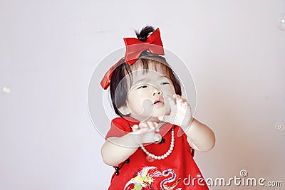 Cute Chinese little baby in red cheongsam play soap bubbles Stock Photo