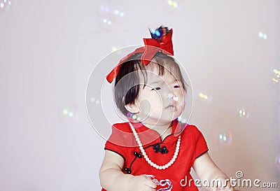 Cute Chinese little baby in red cheongsam play soap bubbles Stock Photo