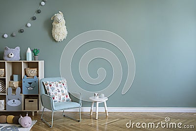 Cute composition of child playing room. Stylish scandi interior design with armchair, wooden shelf, toys, hanging decoration. Stock Photo