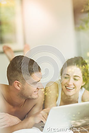 Cute couple lying on bed using laptop Stock Photo