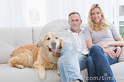 Cute couple relaxing together on the couch with their dog Stock Photo