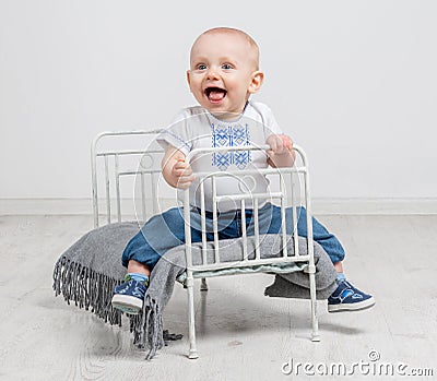 Cute curious baby sitting on a little bed Stock Photo