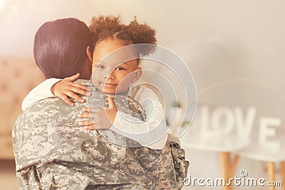 Cute curly girl hugging her mother in military uniform Stock Photo