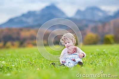 Cute curly toddler girl and her newborn baby brother playing in Stock Photo