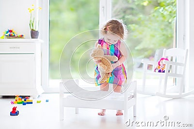 Cute curly toddler girl playing with her teddy bear Stock Photo