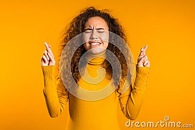 Cute curly young girl praying over yellow background. Woman begging someone. Stock Photo