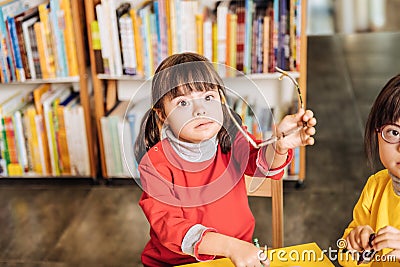 Cute dark-eyed girl with Down syndrome taking her glasses off Stock Photo