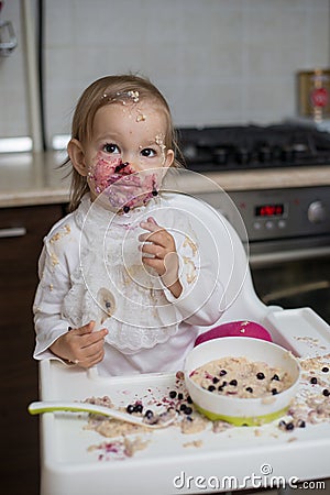 Cute dirty little girl eating healthy porridge Stock Photo