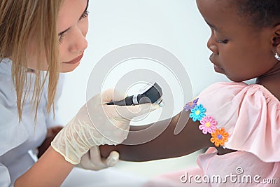 Cute doctor checking skin on shoulders of little afro girl. Stock Photo
