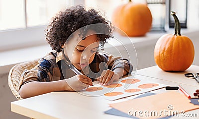 Cute ethnic child boy making Halloween home decorations Stock Photo