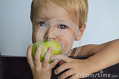 Cute european blond boy eating an green Apple. Healthy food Stock Photo