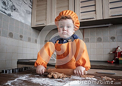 Cute European boy in a suit of the cook makes ginger cookies Stock Photo