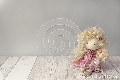 Cute fabric doll girl in pink dress with white rabbit sits on a white wooden table with copyspace Stock Photo