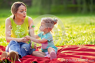 Female child blows soup foam and make bubbles in nature Stock Photo