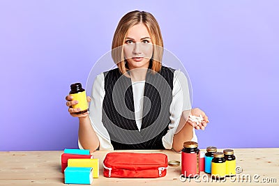 Cute female doctor presents diverse health supplements, handful of pills Stock Photo