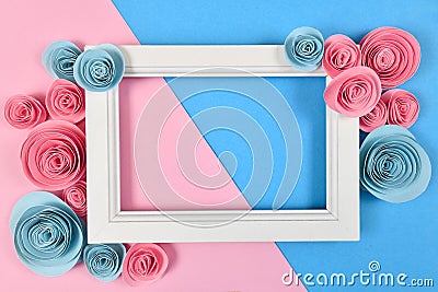 Cute flat lay with empty white picture frame surrounded by romantic paper craft roses on blue and pink background Stock Photo
