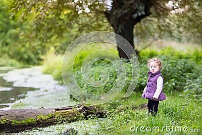 Cute funny baby girl at river shore on cold day Stock Photo