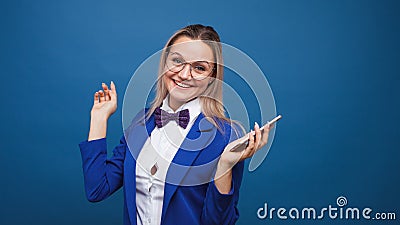 Cute and funny businesswoman in a stylish blue jacket and bow tie uses a smartphone. Stock Photo