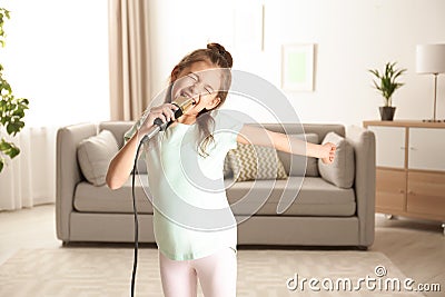 Cute funny girl with microphone in room Stock Photo