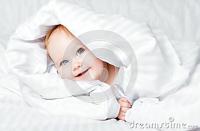 Cute and funny little baby smiling under white blanket. Copy spa Stock Photo