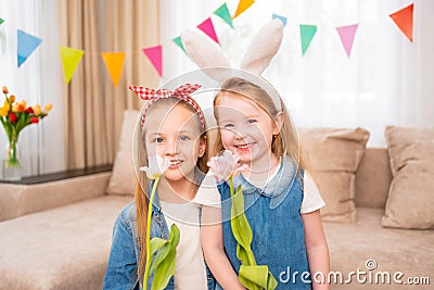little girls with a red headband and rabbit ears hold pink tulip flower in hands Stock Photo