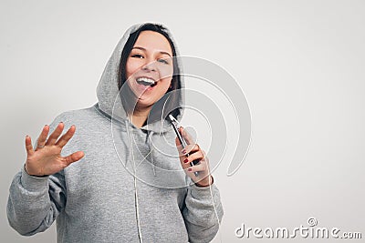 Cute funny young girl the woman in the grey hoodie listening to music from your smartphone through the headset Stock Photo