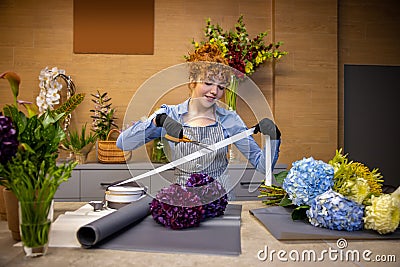 Cute ginger florist looking involved while making a cover for the bouquet Stock Photo