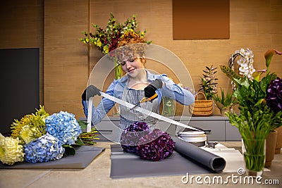 Cute ginger florist looking involved while making a cover for the bouquet Stock Photo