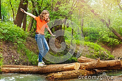 Cute girl balancing while crossing a log bridge Stock Photo