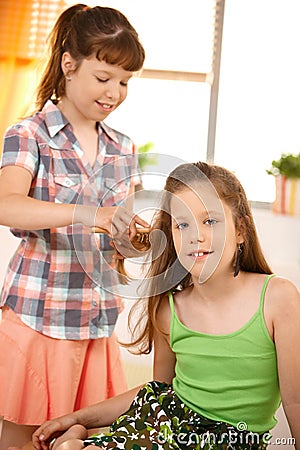 Cute girl combing friend's hair Stock Photo