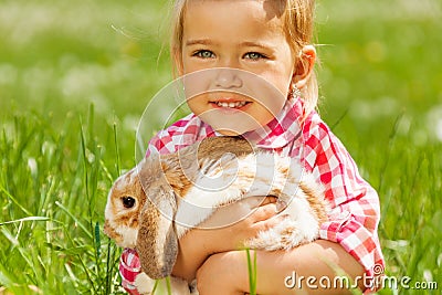 Cute girl cuddling rabbit in green field Stock Photo