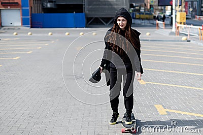 Nice girl with dreadlocks in a hood rides a skateboard Stock Photo