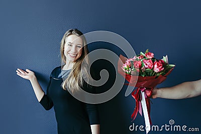 Cute girl getting bouquet of red tulips. Boyfriend giving tulips. Stock Photo