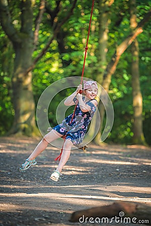 Cute girl having fun on a line swing in summer Stock Photo