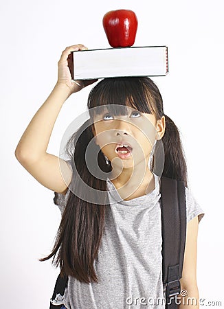 Cute girl holding book and apple on the head Stock Photo