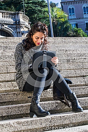 Cute girl looking at her tablet and sitting on stairs Stock Photo