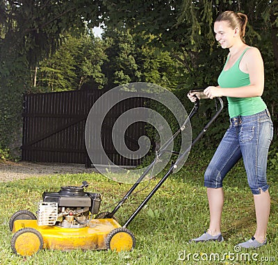 Cute girl moving the grass with yellow lawn mover Stock Photo