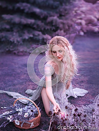 Cute girl in old gray dress with long cut train and open legs sitting on knees and gathering wild flowers, mysterious Stock Photo