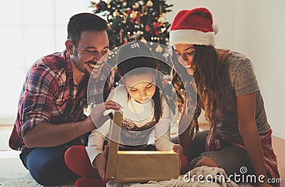 Cute girl opening a present on a Christmas morning with her family Stock Photo