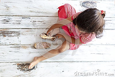 Tender girl putting on her golden slippers Stock Photo