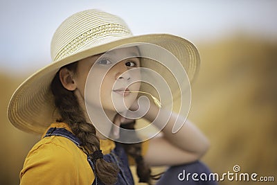 Cute girl in a straw hat, sitting in a field of hay in Eagle Mountain, Ut. Stock Photo