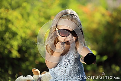 Cute girl with sunglasses outdoors applying lip gloss Stock Photo