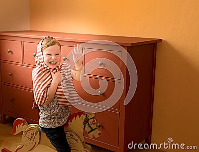 Cute girl swings on rocking horse. Small girl plays and acts like princess. Stock Photo