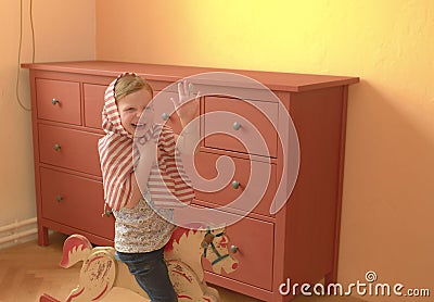 Cute girl swings on rocking horse. Small girl plays and acts like princess. Stock Photo