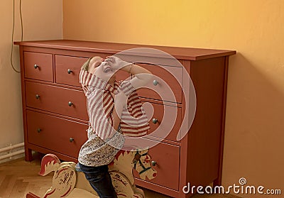 Cute girl swings on rocking horse. Small girl plays and acts like princess. Stock Photo