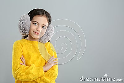 Cute girl wearing stylish earmuffs on grey background. Space for text Stock Photo