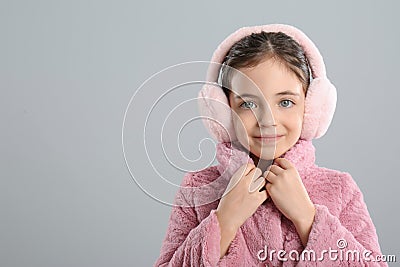 Cute girl wearing stylish earmuffs on grey background. Space for text Stock Photo