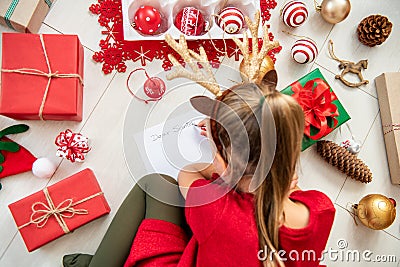 Cute girl writing letter to Santa on livingroom floor. Overhead view of a young girl writing her christmas wishlist. Stock Photo