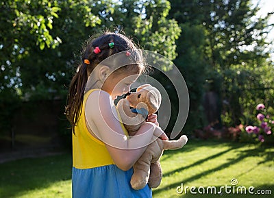 Cute girl of 6-7 years old plays nose to nose with her plush dog Stock Photo